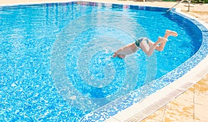 Young boy jumping into swimming pool