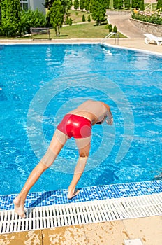 Young boy jumping into swimming pool