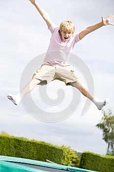 Young boy jumping on trampoline smiling