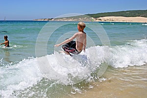 Young boy jumping into wave on a sunny beach photo