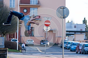 A young boy jumps somersault on the street.