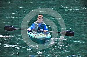 Young boy kayaking on green tinged ocean