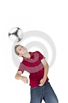 Young boy kicking soccer ball with his head