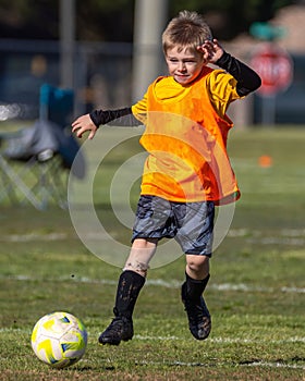 Young boy kicking soccer ball playing goalie during game