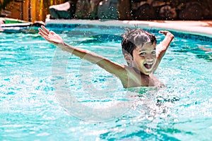 Young boy kid child eight years old splashing in swimming pool having fun leisure activity open arms