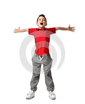 Boy kid in red t-shirt and grey pants spread hands up happy smiling screaming laughing isolated on white photo