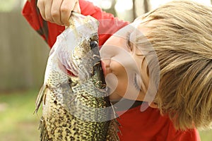 Young boy kissing fish he caught