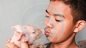 Young boy kissing his pet piglet