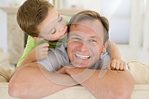 Young boy kissing smiling man in living room