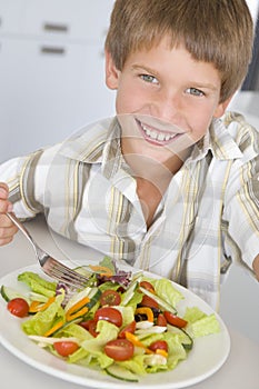 Giovane ragazzo la cucina mangiare insalata 