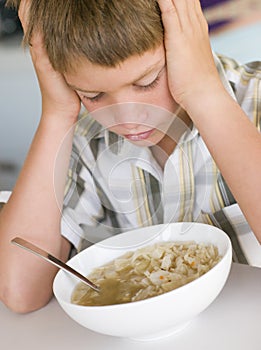 Young boy in kitchen eating soup