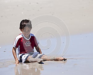 Young Boy Laughing as He Plays in Sand at Beach
