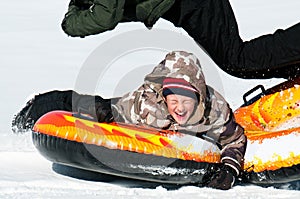 Young boy laughing on a snow tube