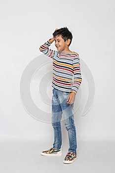 Young boy  laughs at himself, his forgetfulness, awkwardness against  gray background photo