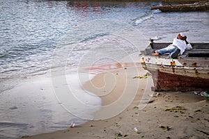 A young boy laying in a boat appearing to be in deep thought