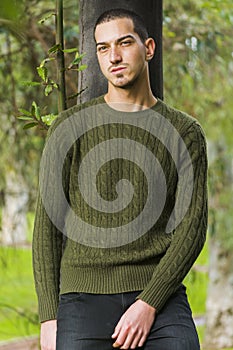 Young boy leaning against tree