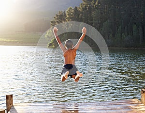 Young boy leaping into lake