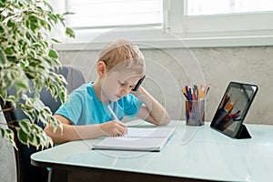 Young boy learn by tablet at home. Distance learning in quarantine. Isolation. Homework