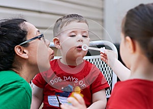 young boy learning how to blow soap bubbles