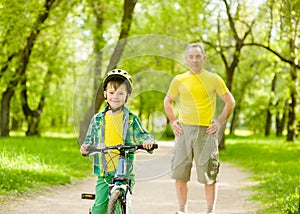 Young boy is learning to ride a bike with his father