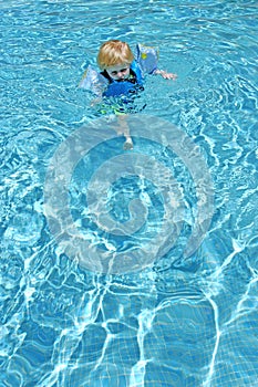 Young boy learning to swim in pool