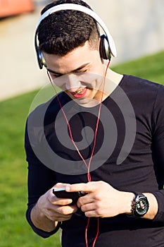 Young boy listening to music with smartphone in the street