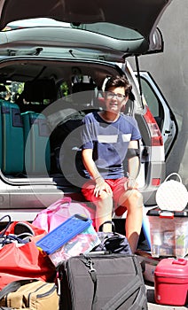 Young boy loads the car with a lot of luggage before leaving for