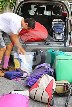 Young boy loads the trunk of the car with a lot of luggage  befo