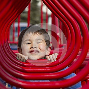 Young boy looking in the hoops of a playground