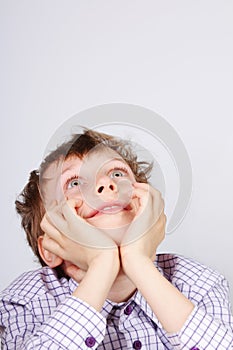 Young boy looking upwards surprised and smiling on grey background