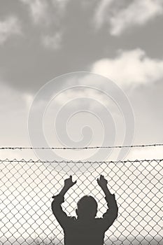 Young boy looks out from the net towards freedom