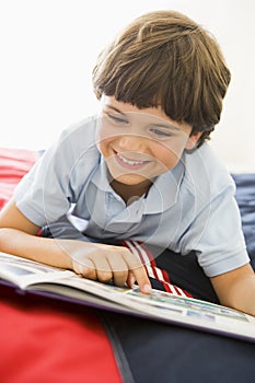 Young Boy Lying Down On His Bed Reading A Book