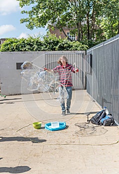 Young boy makes huge soap bubbles on the street