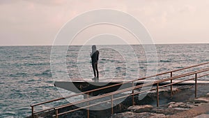 Young boy making photo of stormy sea. Man takes picture of ocean. Lonely boy standing at promenade