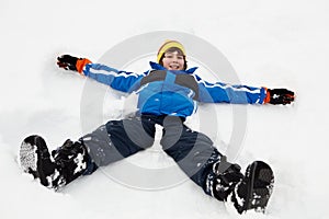 Young Boy Making Snow Angel On Slope