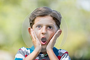 Young boy making surprise expression while pulling out funny faces