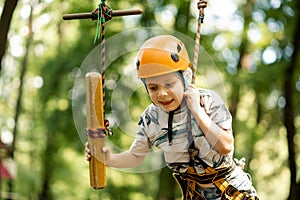 A young boy in a mountain belay and a flip flop goes through an obstacle course. Active, sporty activity in the summer for a child