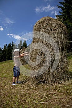 Young boy next to a haystack