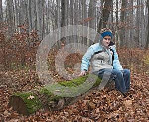 Young boy on old log in forest