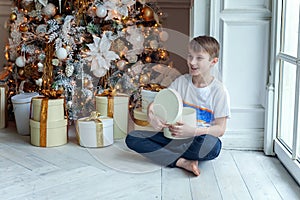 Young boy opens a gift under a Christmas tree