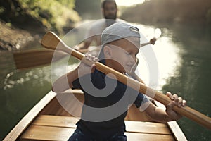 Young boy paddling canoe on the lake with his dad
