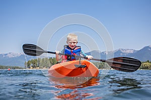 Young Boy paddling a kayak on a beautiful mountain lake