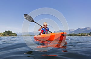 Young Boy paddling a kayak on a beautiful mountain lake