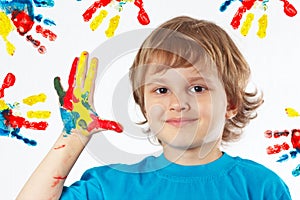 Young boy with painted hands on background of hand prints