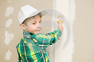 Young boy painting the wall with paintbrush