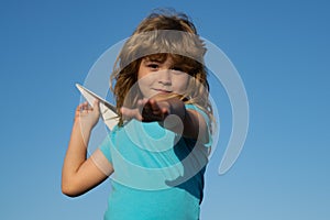 Young boy with paper plane against blue sky. Kid playing with paper airplane on sunny day.