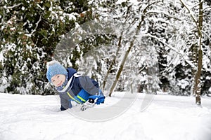 Young boy plaing wiht snow in winter forest