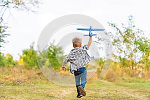 Young boy play with toy airplaine in hands. Happy Kid is playing in park outdoors photo