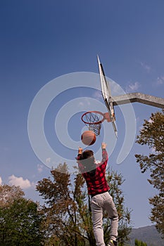 Young boy is playing basketball outdoors.