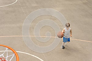Young boy playing basketball running with the ball